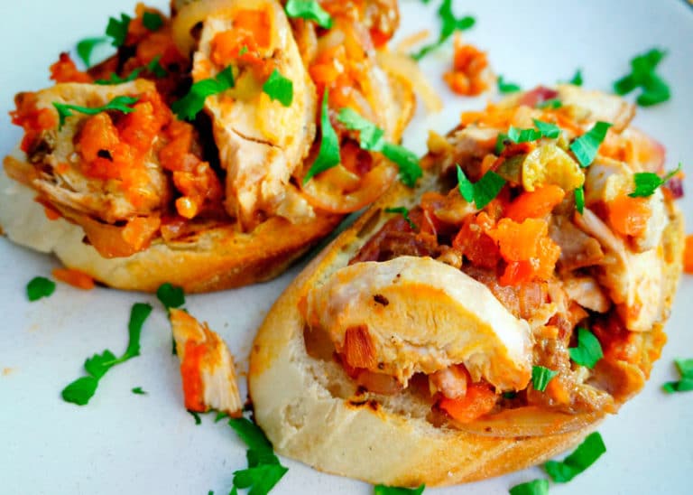 Теплые бутерброды из белого хлеба с жареной куриной грудкой, помидором, красным луком, оливками и анчоусами фото