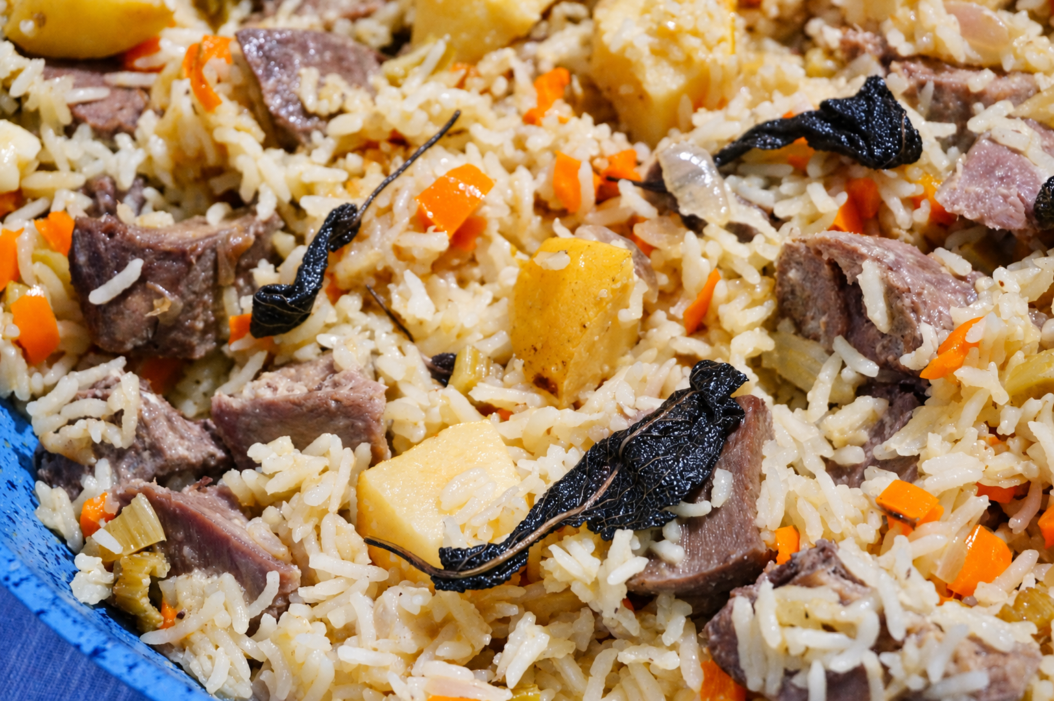 Плов с кусочками свиного языка, айвой и листьями шалфея — крупный план